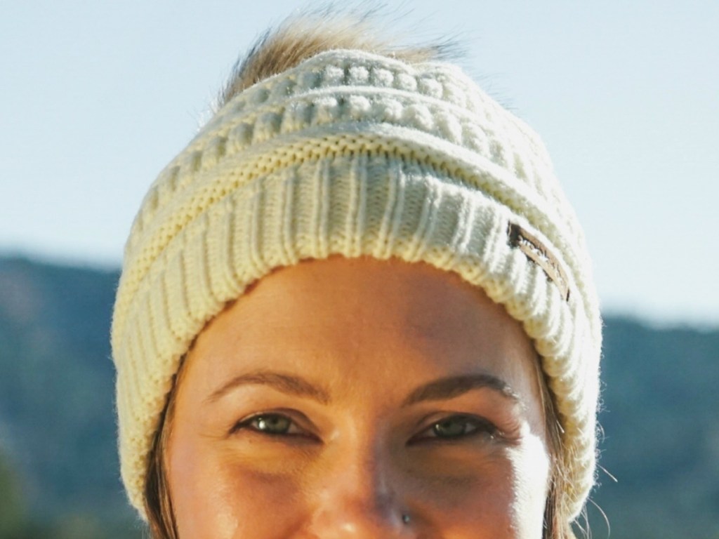 Woman wearing ivory beanie cap with faux fur, outdoors