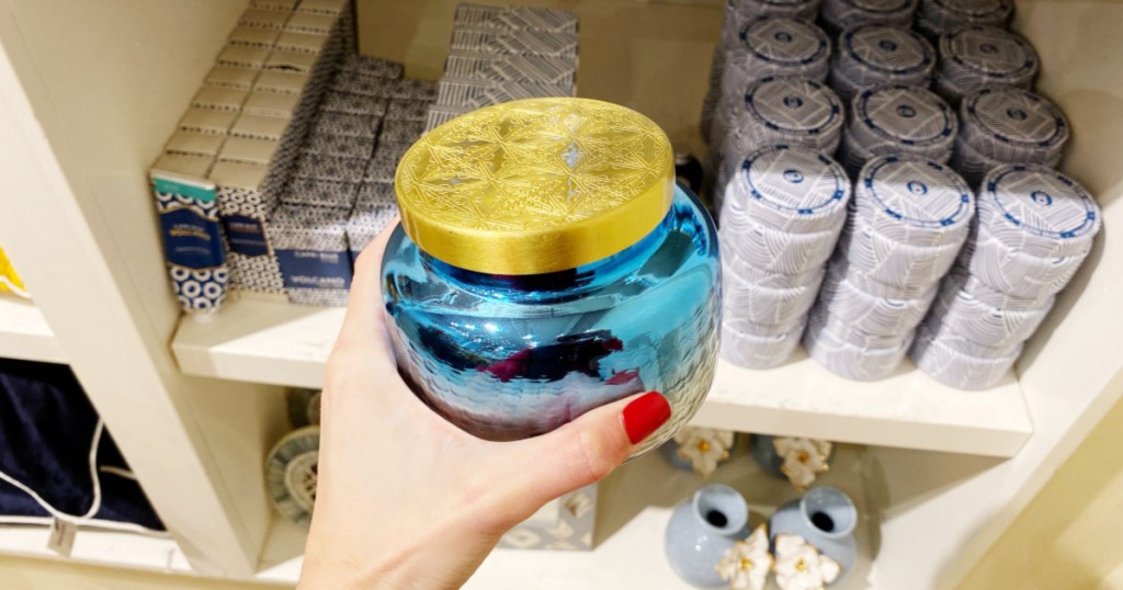 woman hand holding Capri Blue Iridescent Jar Candle in store