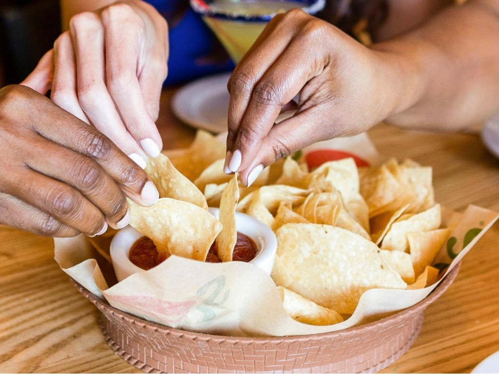 Three friends sharing a bowl of Chili's chips in restaurant