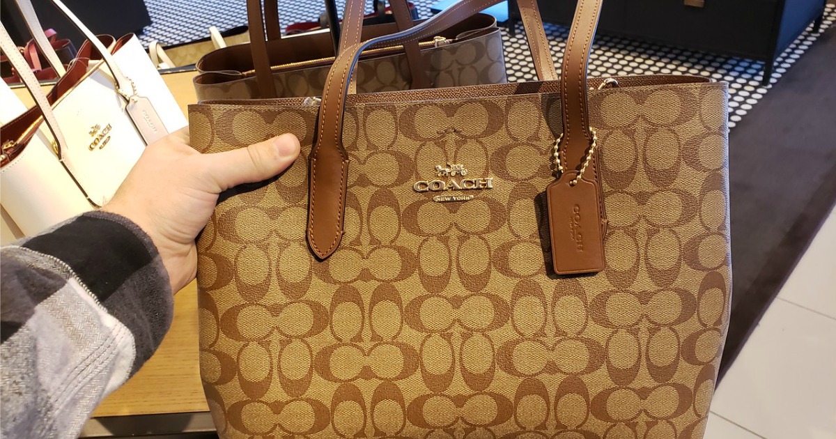 hand holding a Coach Tote on display in a store
