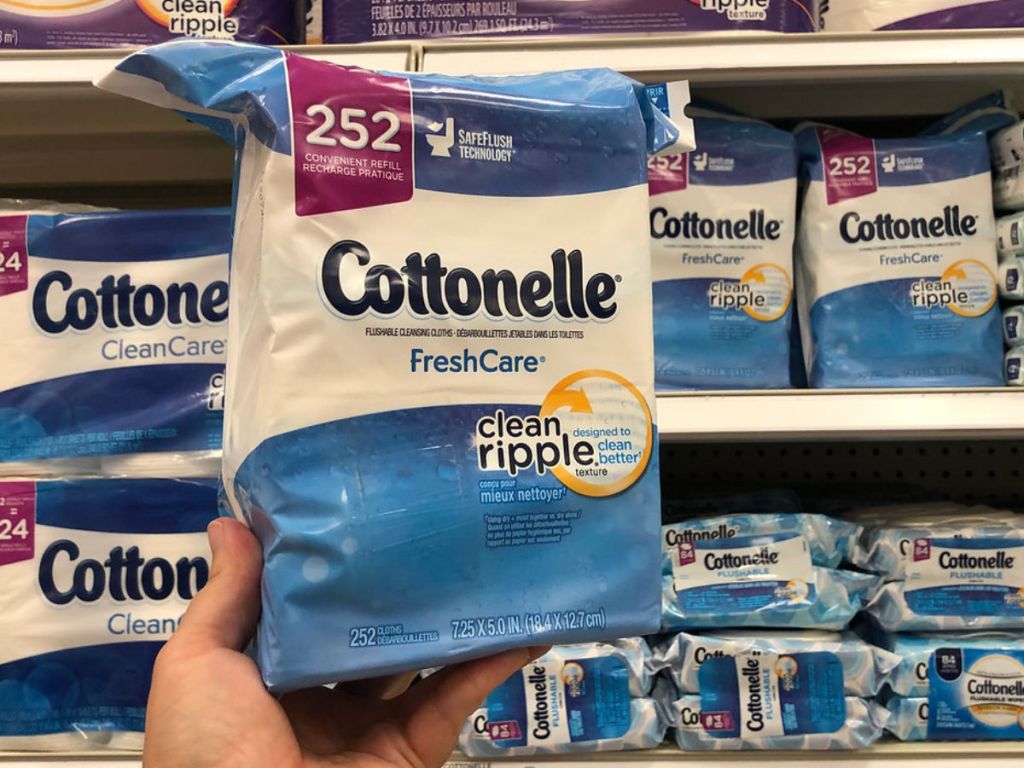 hand holding Cottonelle FreshCare 252 Count in store with more wipes behind