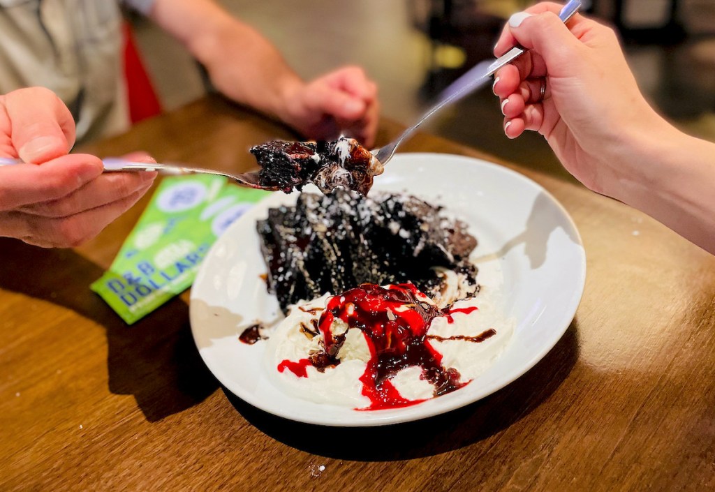 hand holding forks with chocolate cake on top