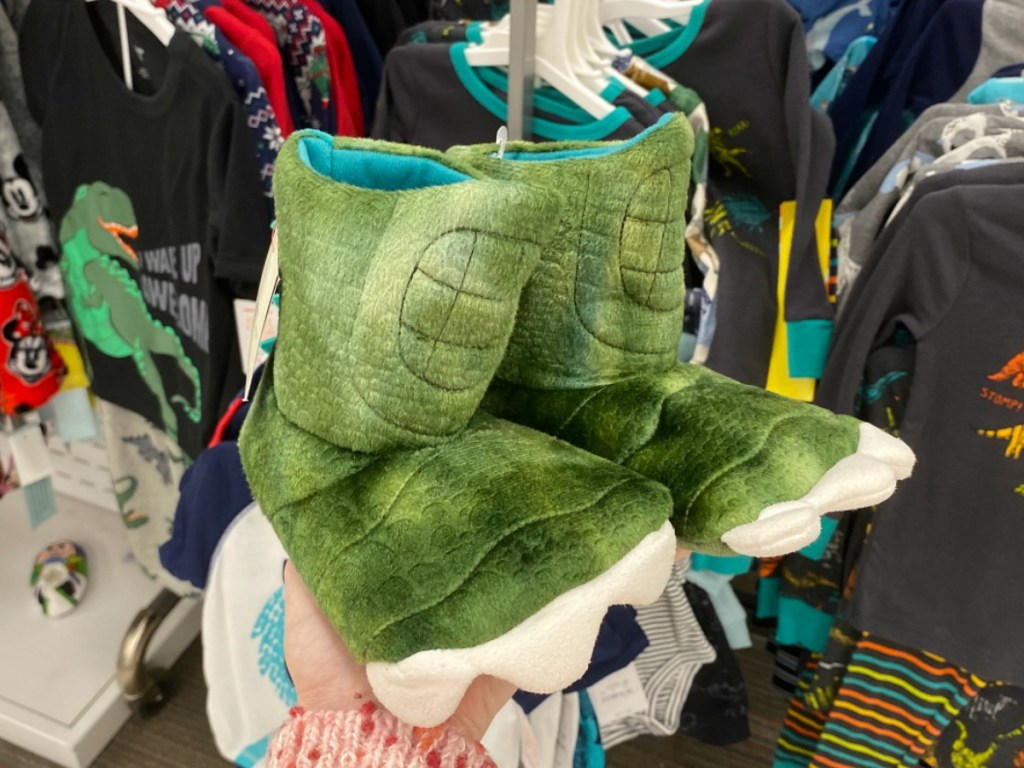 Baby & Toddler Dinosaur themed slippers in a pair in hand at Target store