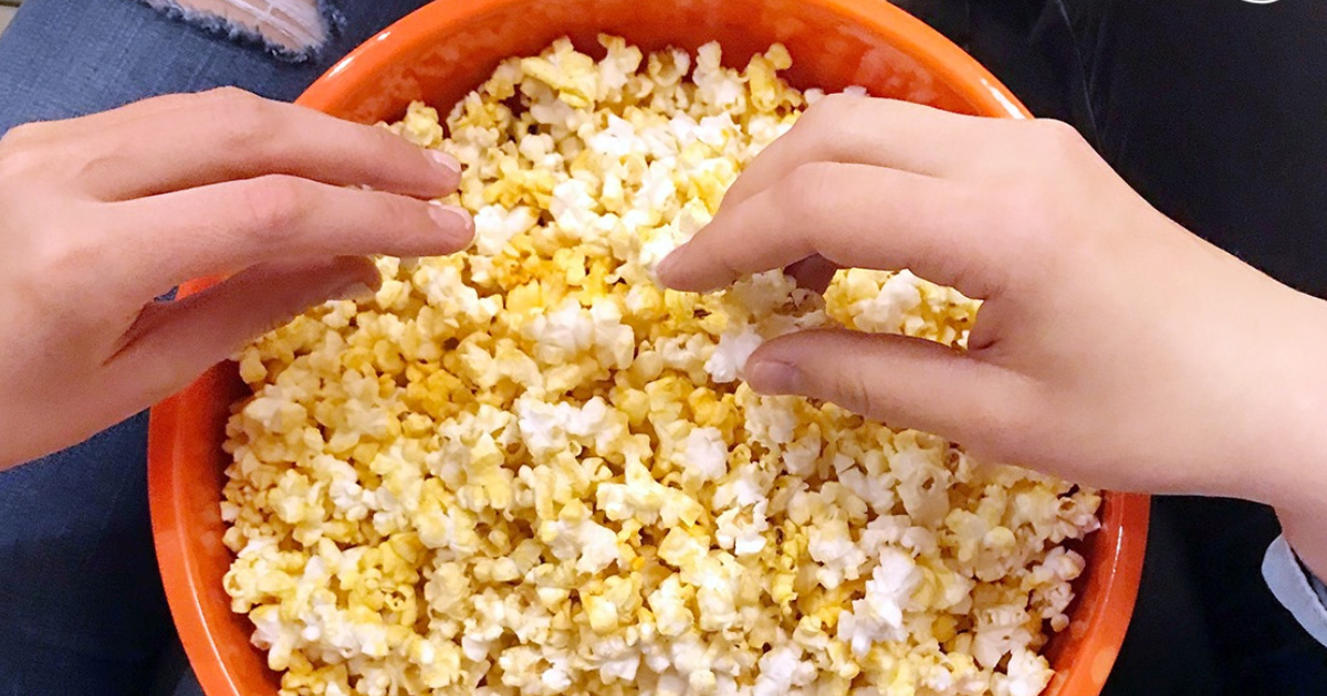 Hands reaching into Jolly Time Popcorn Bowl
