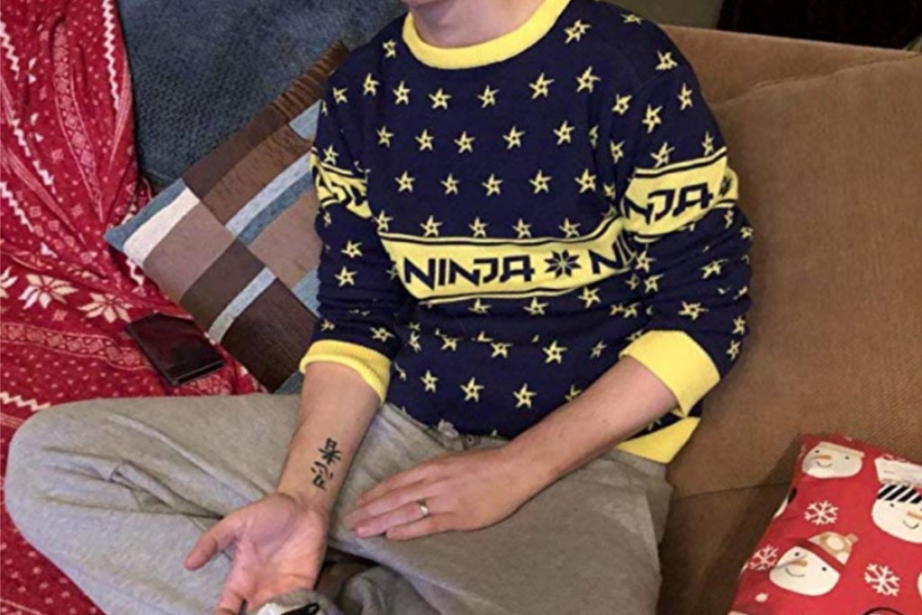ninja wearing Ninja Video Game Streamer Shuriken Sweater on the couch with presents