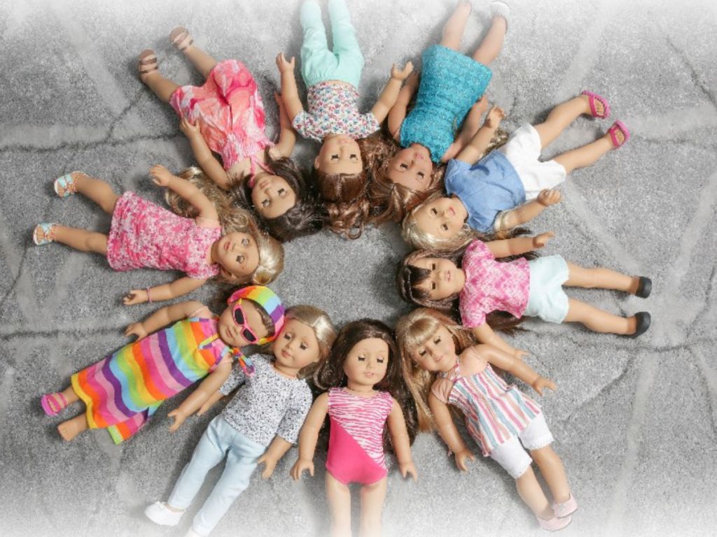 Dolls laid out on a grey blanket in outfits