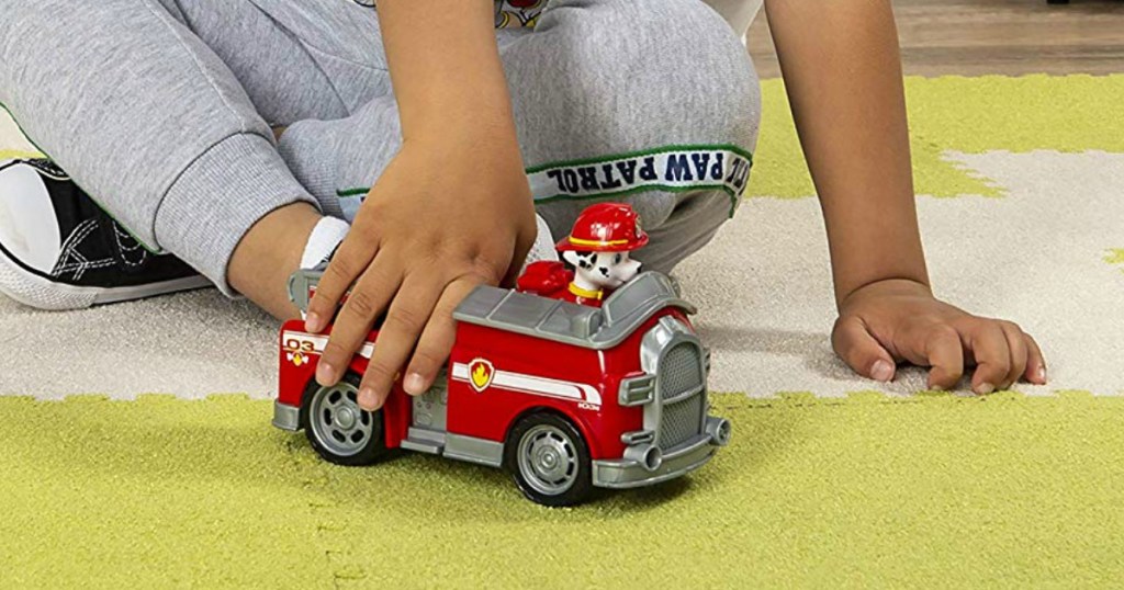 Boy playing with a Paw Patrol fire truck and figure