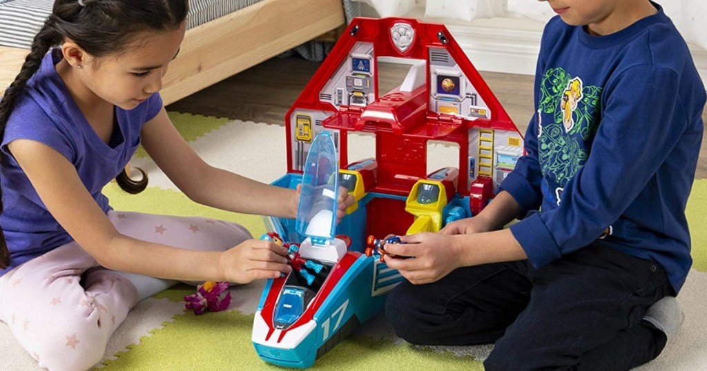 Two kids playing with a Paw Patrol Playset 