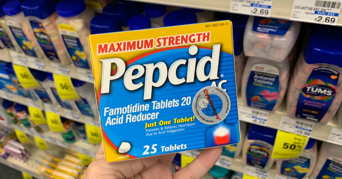 Hand holding Pepcid in front of shelf 