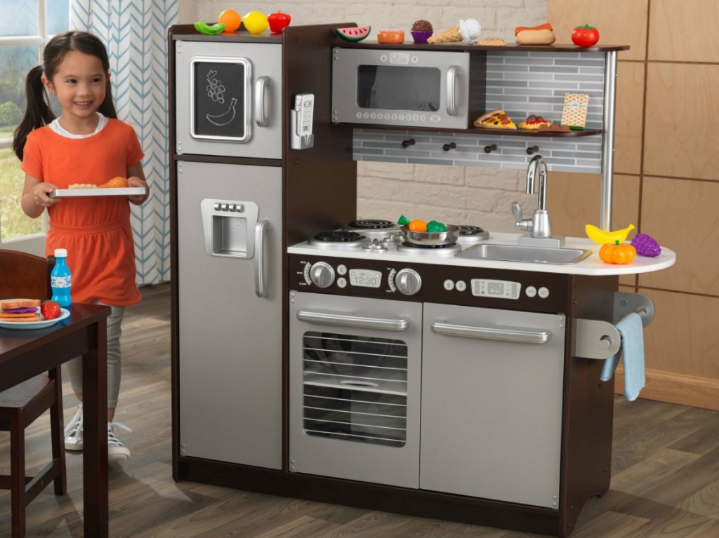 Young girl playing with a toy kitchen and play food