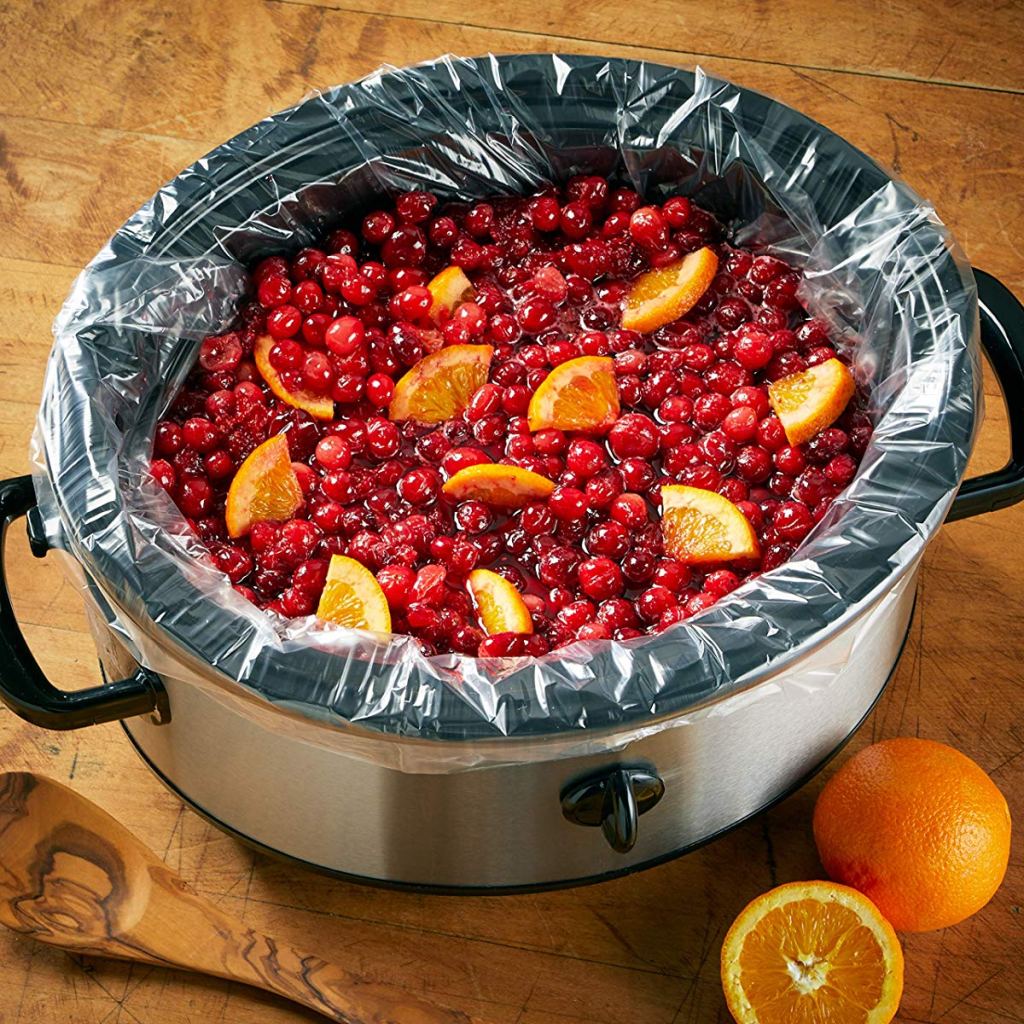 Slow cooker with liner and cranberries with oranges