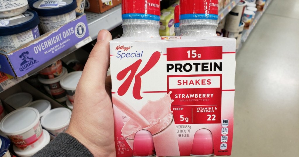 Man holding four-pack of strawberry protein shakes in store