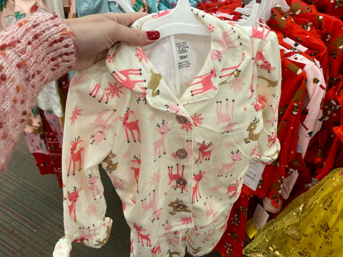 Toddler holiday themed pajamas on hanger in hand in-store at Target