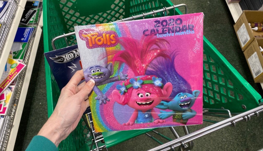 hand holding a Trolls Calendar in a cart