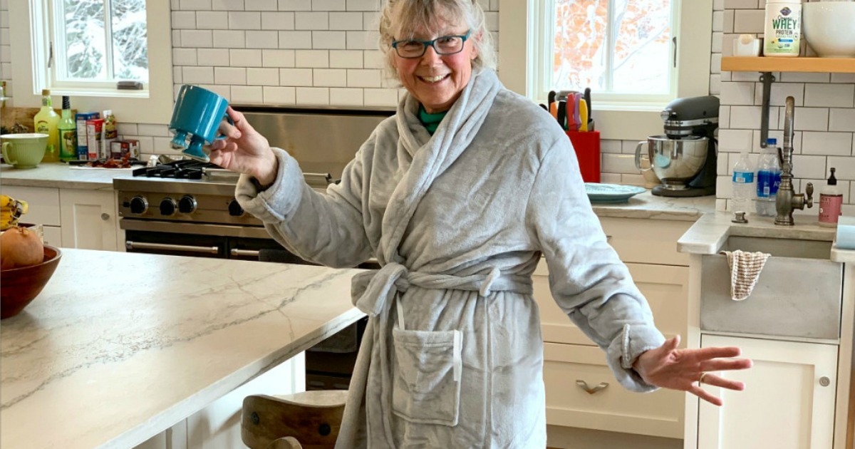 Women's in robe standing in kitchen holding up a coffee mug
