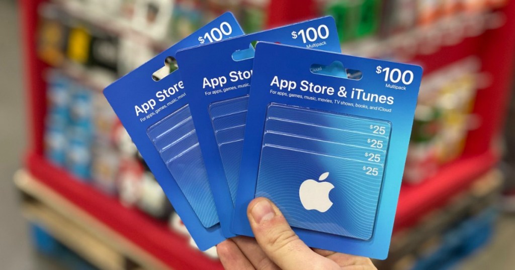 hand holding 3 iTunes gift cards in store