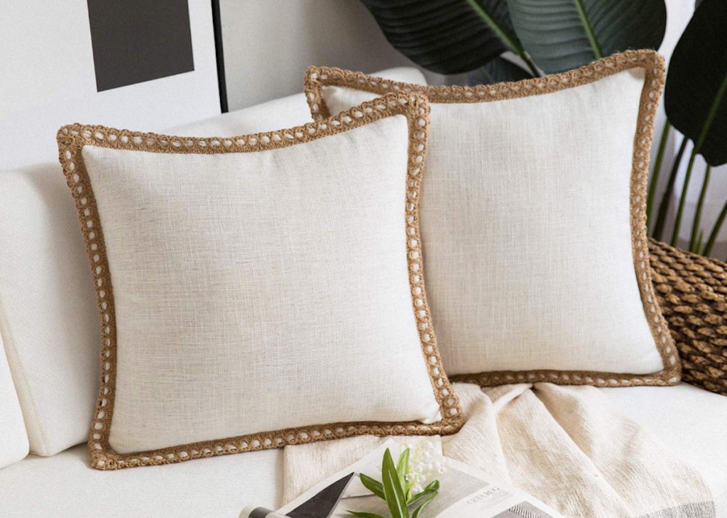 two cream pillow with burlap trim sitting on white couch