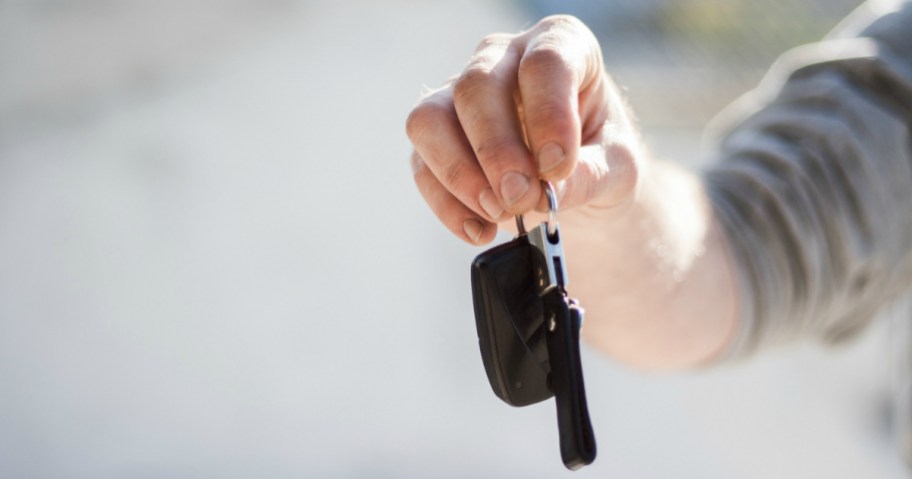a car rental person holding keys to a car that was perhaps rented with Costco travel deals