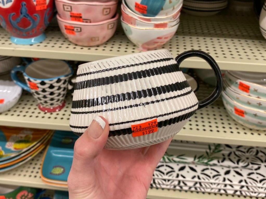 hand holding mug that is black and white in front of store display