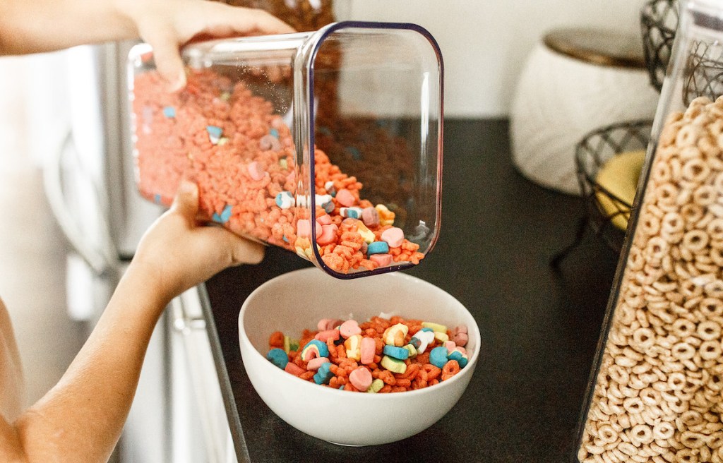 kid holding oxo container pouring pink cereal in white bowl