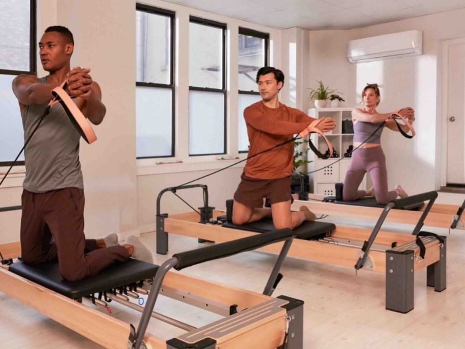3 people working out on pilates reformers