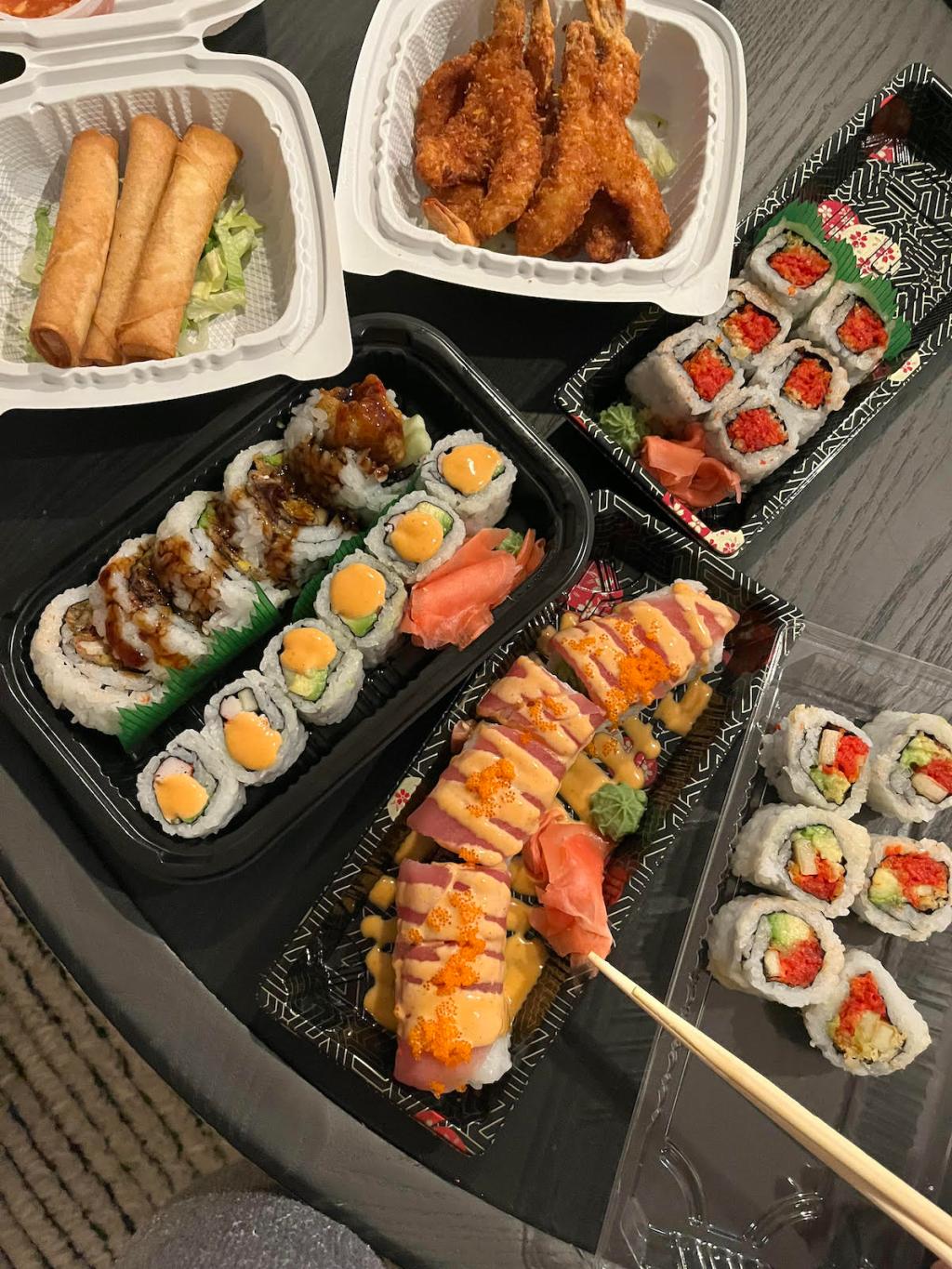 tons of sushi on table in to go containers