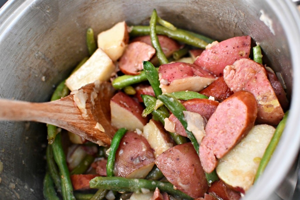 stirring one-pot sausage green beans and potatoes