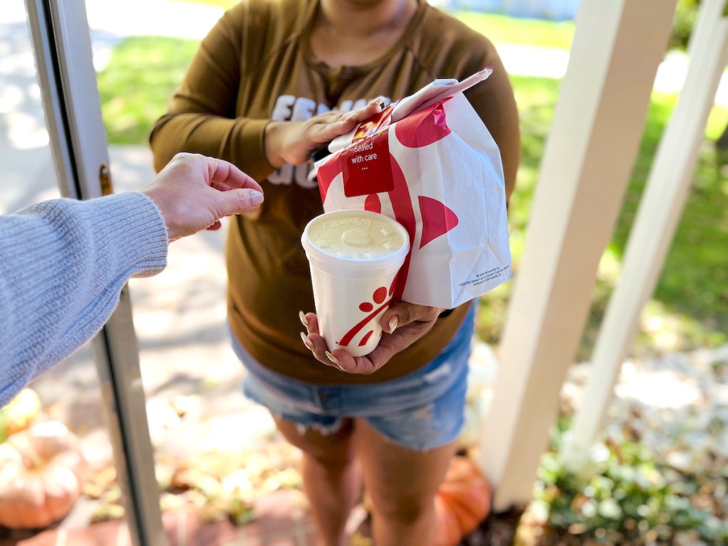 woman standing in doorway holding chick fil a to go food from best food delivery service