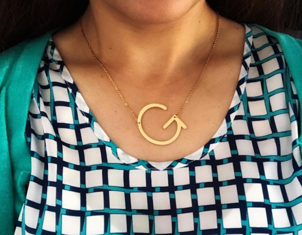 woman wearing g shaped monogram necklace and check shirt