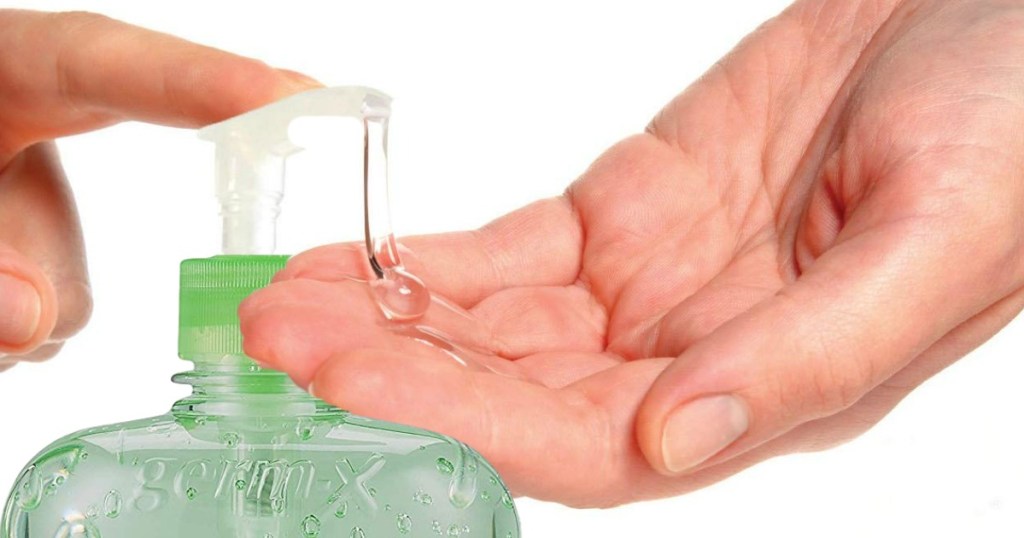 hands pushing down bottle of hand sanitizer