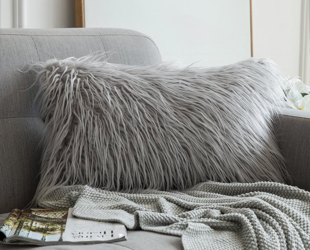 gray fur throw pillow on gray couch with blanket and magazine