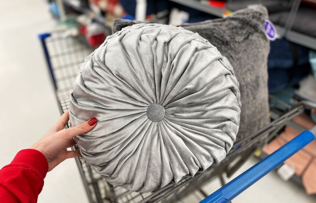 hand holding a round tufted gray throw pillow in walmart cart