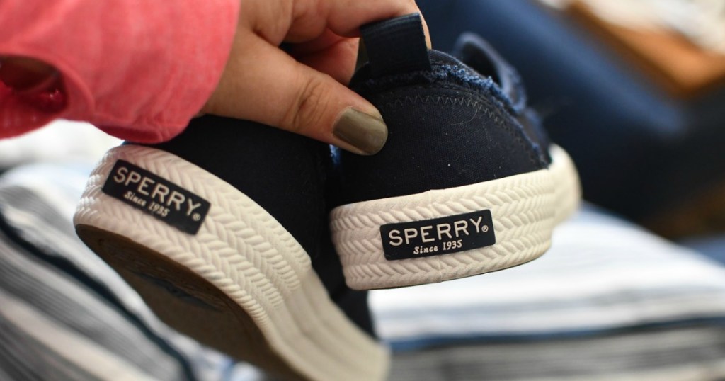 woman's hands holding Sperry shoes