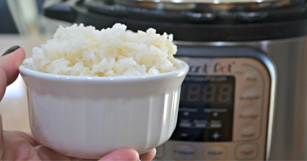 hand holding rice with instant pot in background