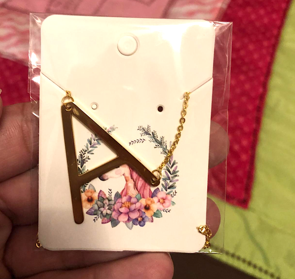 holding gold necklace with the letter A 