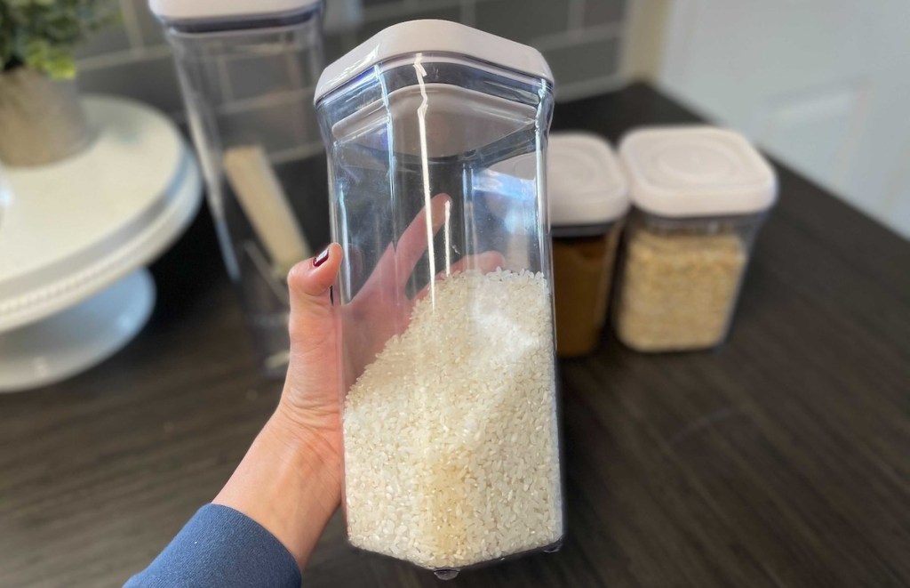 hand holding clear oxo container with white rice inside