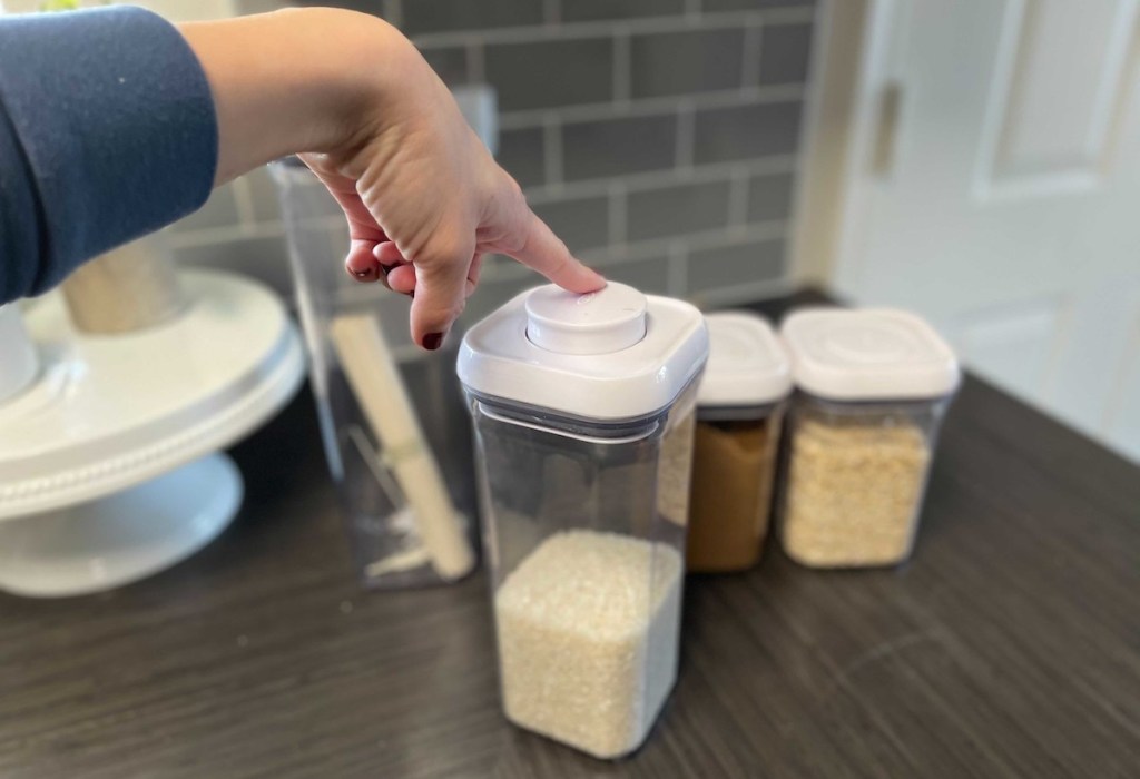 finger pushing on top of oxo food storage container