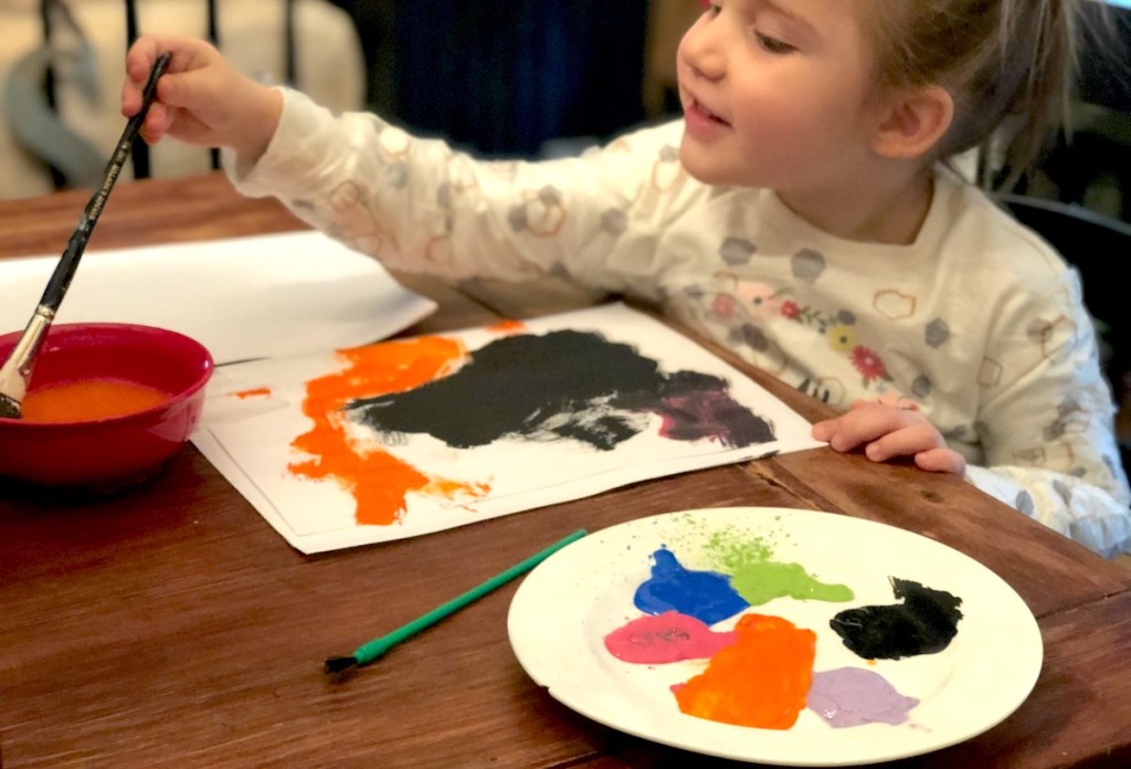 girl painting picture with paintbrush and press n seal plastic on clothes