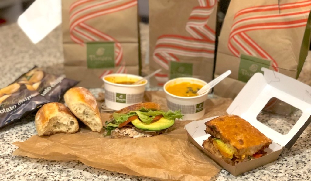 various sandwiches and soup with panera bags sitting on kitchen counter