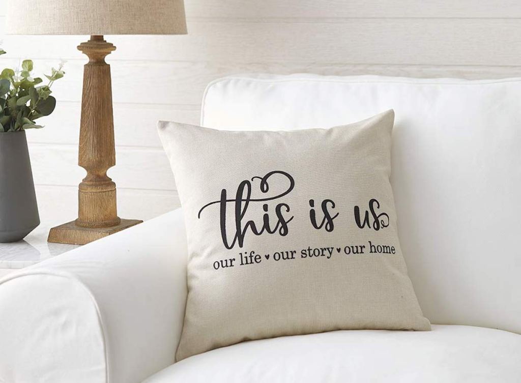 cream this is us quote pillow sitting on white couch next to lamp and plant 