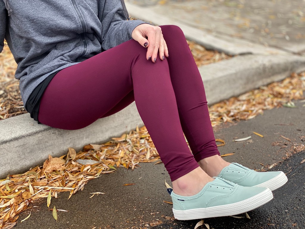 woman sitting on sidewalk wearing Sperry shoes and leggings