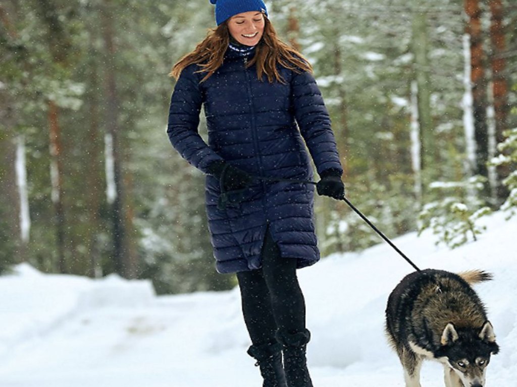 woman walking a husky in the forest wearing eddie bauer down parka
