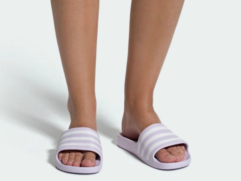 woman's legs with purple pair of slide on shoes