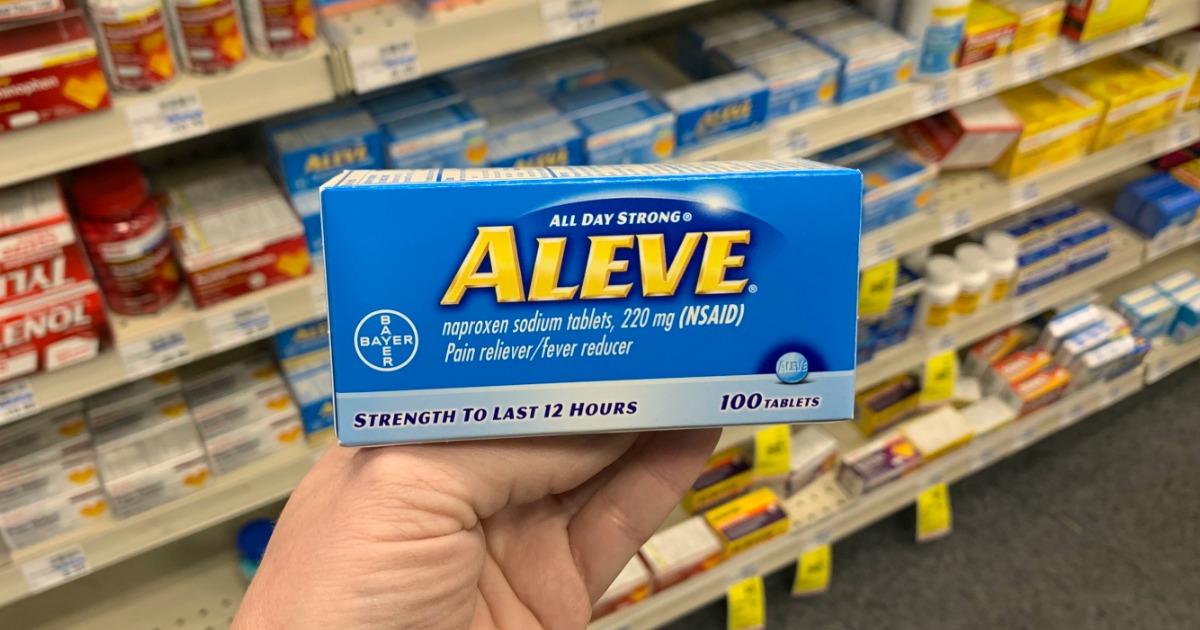 Hand holding aleve in front of shelf