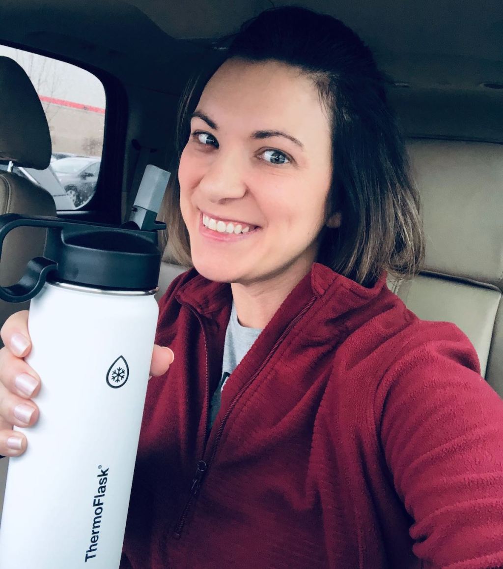 woman smiling holding white and black reusable bottle