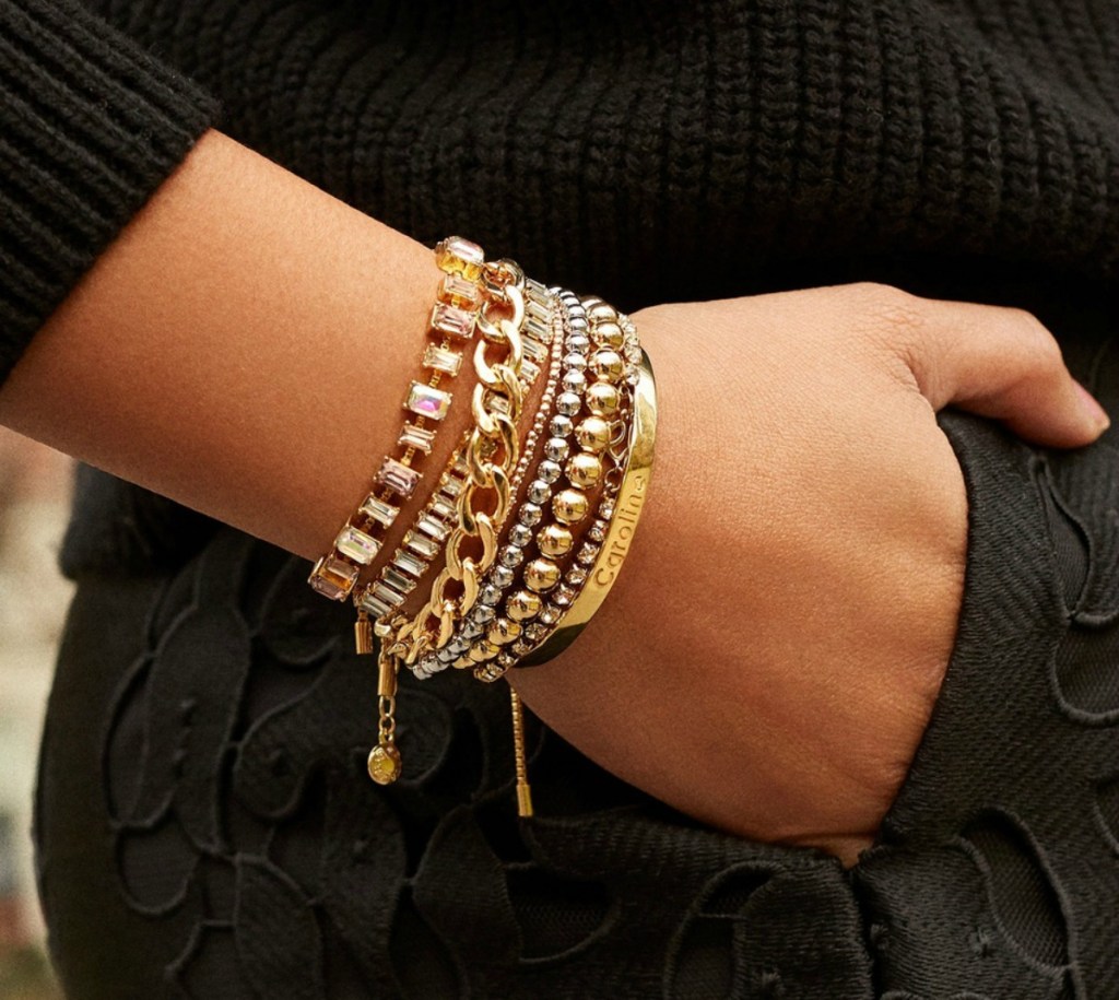 woman in black wearing multiple gold bracelets