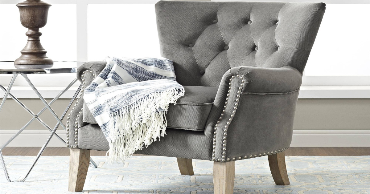 rolled arm accent chair in gray, with cream blanket hanging over the side and and end table with a lamp beside it