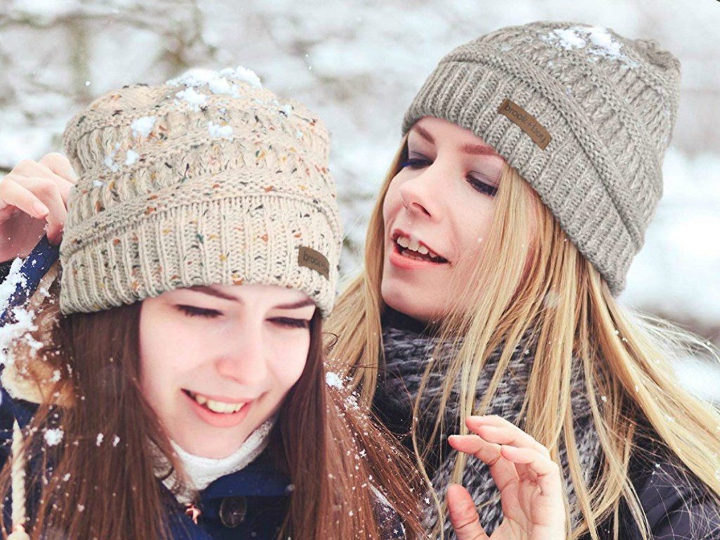 Two women in the snow wearing knit beanie hats