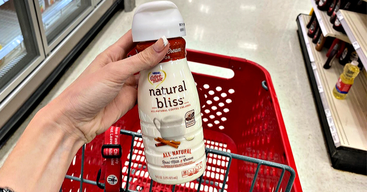 Coffee-Mate Natural Bliss Creamer in hand with Target shopping cart in back