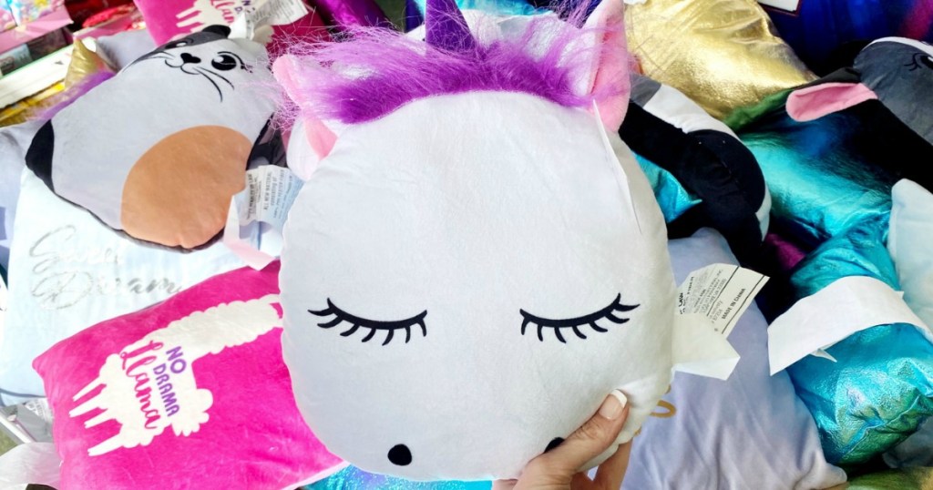 Unicorn themed squishy pillow in hand near in-store display